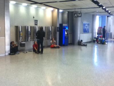 People lined up sitting on the floor to use electrical outlets in an airport